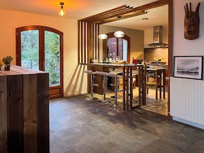 Eine moderne Küche mit einer zentralen Kochinsel, Holzbalken und Pendelleuchten.
