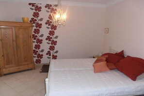 Ein Schlafzimmer mit einem Bett, einem Holzschrank, einer Chandelüster und einer Wand mit einem Blumenmuster.