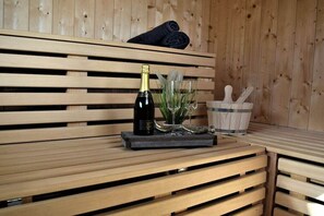 Eine hölzerne Bank mit einer Champagnerflasche, einem Glas und einem kleinen Topfpflanz auf einem Tablett.