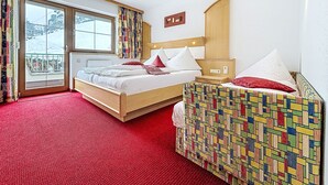 A hotel room with a bed, a small bedside table, a chair, a window with curtains, and a view of a snowy landscape. - Wiesenhof by Interhome (Kappl)