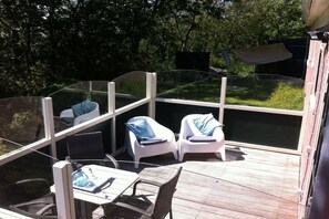 Eine Terrasse mit Glasveranda, weißen Liegestühlen und einem Tisch mit Stühlen.