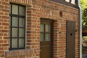 A brick building with a window, a door, and a small vent. - The yellow holiday home (Irmenach)