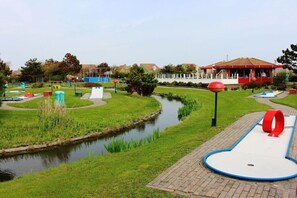 Ein Park mit einem Wasserkanal, Spielgeräten und einem Gebäude mit rotem Dach.