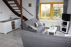 Ein Wohnzimmer mit einer Couch, einem Fernseher, einem weißen Schrank und einer Treppe.