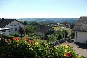 A residential area with houses, a flag, and a view of distant hills. - Holiday home with 8 bedrooms (Medebach-Düdinghausen)