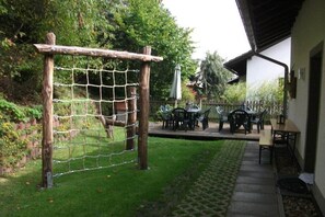 A patio area with a wooden pergola and a netted play structure. - Holiday home with 8 bedrooms (Medebach-Düdinghausen)