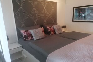 Una habitación de hotel con cama, mesita de noche, lámpara y cabecera estampada.