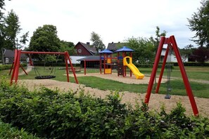 Ein Spielplatz mit Schaukeln, einer Rutsche und einer Kletteranlage.