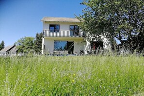 A two-story building with a balcony, surrounded by tall grass and trees. - Sauerlandhaus Küstille (Medebach)
