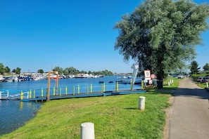 Joenrantareitti, jossa on silta, veneitä ja puu.