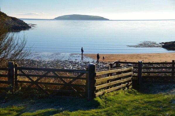 A coastal scene with a wooden gate, a beach, and a calm sea. - House - Sleeps 6 - Pet Friendly - Parking (Castle Douglas)