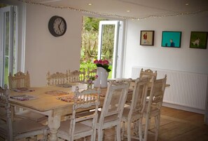Un comedor con una mesa y sillas de madera, un florero con flores y un reloj en la pared.