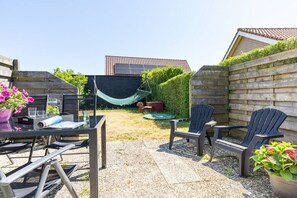Eine Terrasse im Freien mit Tisch, Stühlen und einer Hängematte.
