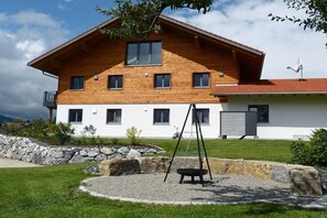 Ein zweistöckiges Holzhaus mit weißer Fassade, einer Steinmauer und einer Schaukel im Garten.