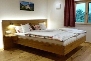Ein hölzernes Bett mit Kopfteil, einem Nachttisch und einem Fenster mit Vorhängen.