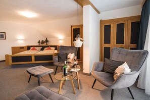 Ein modernes Zimmer mit einem Bett, zwei Sesseln, einem Glastisch und einer Pendelleuchte.