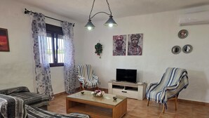 Una sala de estar con sofá, sillón, televisor y una mesa de centro.