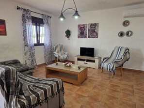 A living room with a sofa, armchair, TV, and a coffee table. - Cuervi house with private pool in Conil. (Conil De La Frontera)
