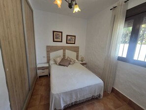 A bedroom with a bed, bedside tables, a wardrobe, and a window with curtains. - Cuervi house with private pool in Conil. (Conil De La Frontera)
