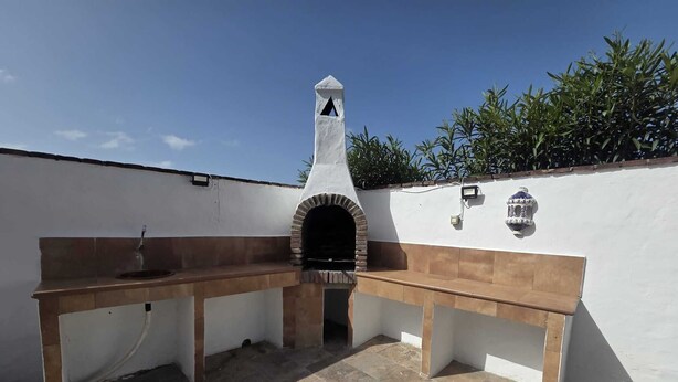 Cocina exterior con encimera de piedra, un lavamanos y una chimenea.