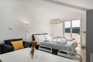 Ein modernes Schlafzimmer mit Bett, Nachttisch, Lampe und Blick ins Freie.