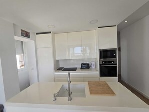 Eine moderne Küche mit weißen Schränken, einer Spüle aus Edelstahl, einer Mikrowelle und einem Backofen.
