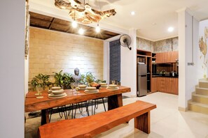 A dining area with a wooden table set for four, a bench, and a statue. - VILLA NARADA -TROPICAL PARADISE VILLA - PRIVATE POOL - CONVENIENT LOCATION (seminyak)