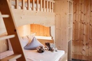 Ein hölzernes Etagenbett mit einer Leiter, einem Kopfkissen und zwei Stoffkoalas auf dem Bett.