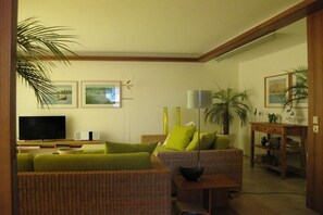 Ein Wohnzimmer mit Fernseher, zwei Sofas, einem Couchtisch und einem Bücherregal.