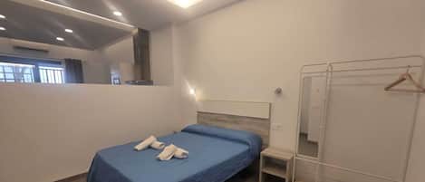 A bedroom with a bed, a bedside table, a wardrobe, and a mirror.