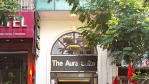 Un hotel llamado 'The Aura Suite' con un amplio ventanal de arco y un cartel sobre la entrada.