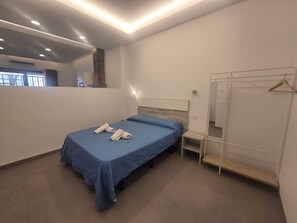 Ein Schlafzimmer mit einem Bett, einem Nachttisch, einem Kleiderschrank und einem Spiegel.