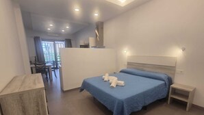 A modern hotel room with a large bed, a desk, and a view of the outdoors. - Apartment 2 Virgen de la Luz (Conil De La Frontera)