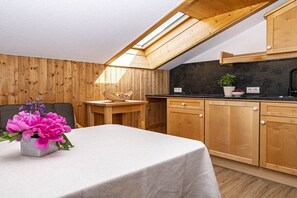 Une cuisine avec des meubles en bois, un plan de travail noir et une lucarne.