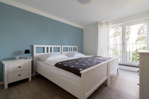 A bedroom with a bed, a nightstand, a lamp, and a window with a view. - Holiday apartment with 2 bedrooms (Tübingen)