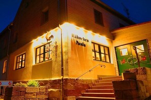 Ein Gebäude mit einem Schild, auf dem 'Hahnen Paula' steht, und einer grünen Tür mit einem Fahrradsymbol.