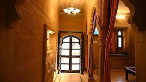 A corridor with an ornate doorway, a chandelier, and a bench. - hotel kalyan haveli jaisalmer (Jaisalmer)