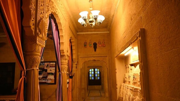 An ornate corridor with a chandelier, a window with stained glass, and a wall with carved details. - hotel kalyan haveli jaisalmer (Jaisalmer)