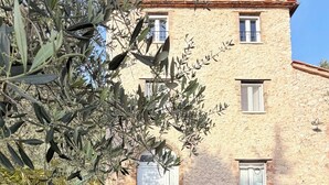 En bygning i sten med en rustik facade, en belagt sti og frodig vegetation.