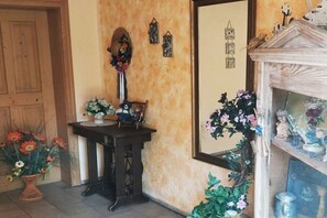 A room with a wooden door, a dark wooden table with a vase of flowers, a mirror on the wall, and a shelf with various items. - Holiday apartment in Regen with swimming pool (Regen)