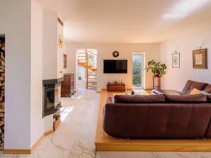 Sala de estar com lareira, sofá, televisão e escada para um andar superior.
