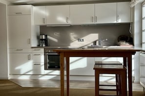 Eine moderne Küche mit weißen Schränken, einer Kaffeemaschine und einem Spülbecken.