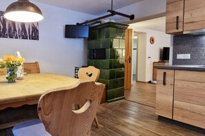 Ein Essbereich mit Holztisch und -stühlen, einer Wand mit grünen Fliesen und einer Küche mit Holzschränken.