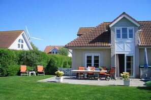 A house with a patio, outdoor seating, and a wind turbine.