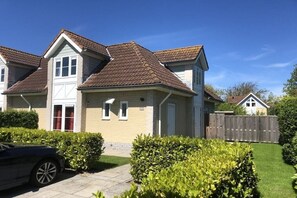 Un immeuble résidentiel doté d’un toit à deux versants, d’un garage et d’une cour arrière clôturée.