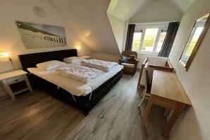 Une chambre Ă coucher avec un lit, des tables de chevet, une chaise, un bureau et une fenĂŞtre.