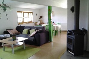 Ein Wohnzimmer mit einer Couch, einem Couchtisch, einem Kamin und einem Essbereich mit Stühlen und einem Tisch.