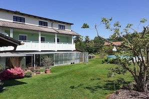 Ein zweistöckiges Gebäude mit Balkon, Gewächshaus und gepflegtem Rasen.