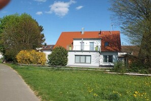 A two-story house with a red roof, white walls, and a front garden with yellow flowers. - Holiday apartment with 1 bedroom (Tübingen)