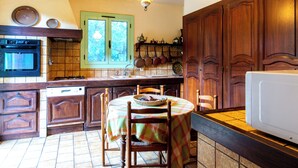 Une cuisine avec des meubles de rangement en bois, une cuisinière, un lave-vaisselle et une table à manger avec des chaises.